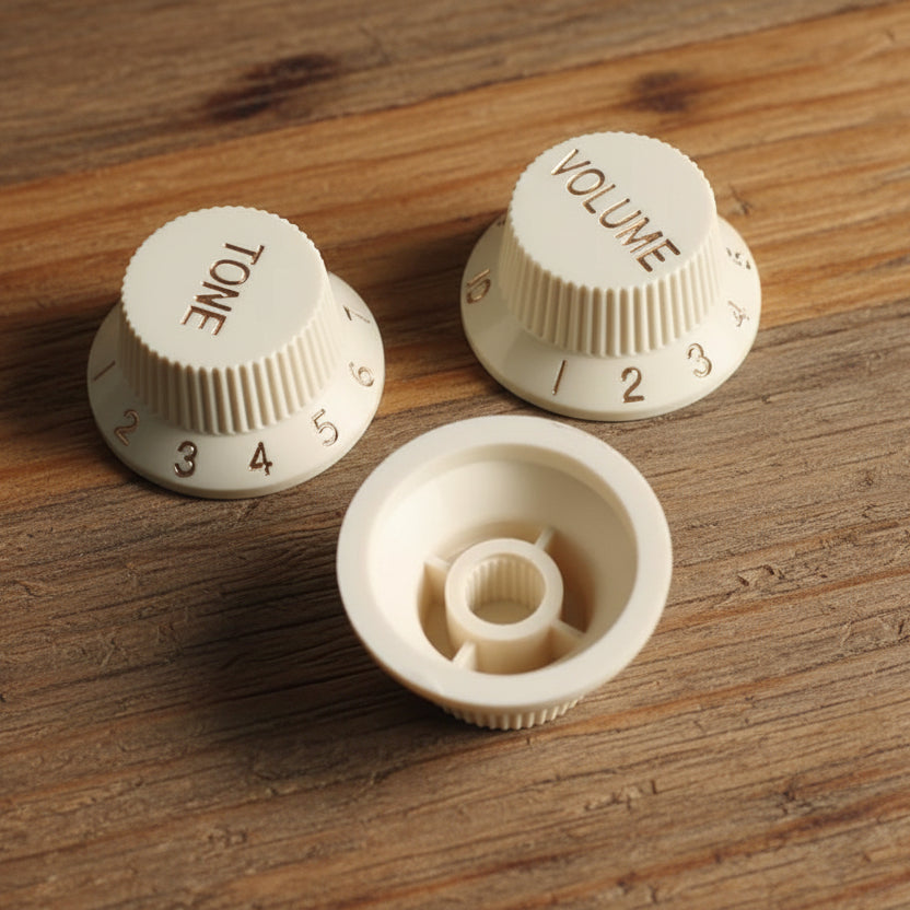 Stratocaster-style volume and tone knob set, cream finish, 3-piece, on workbench